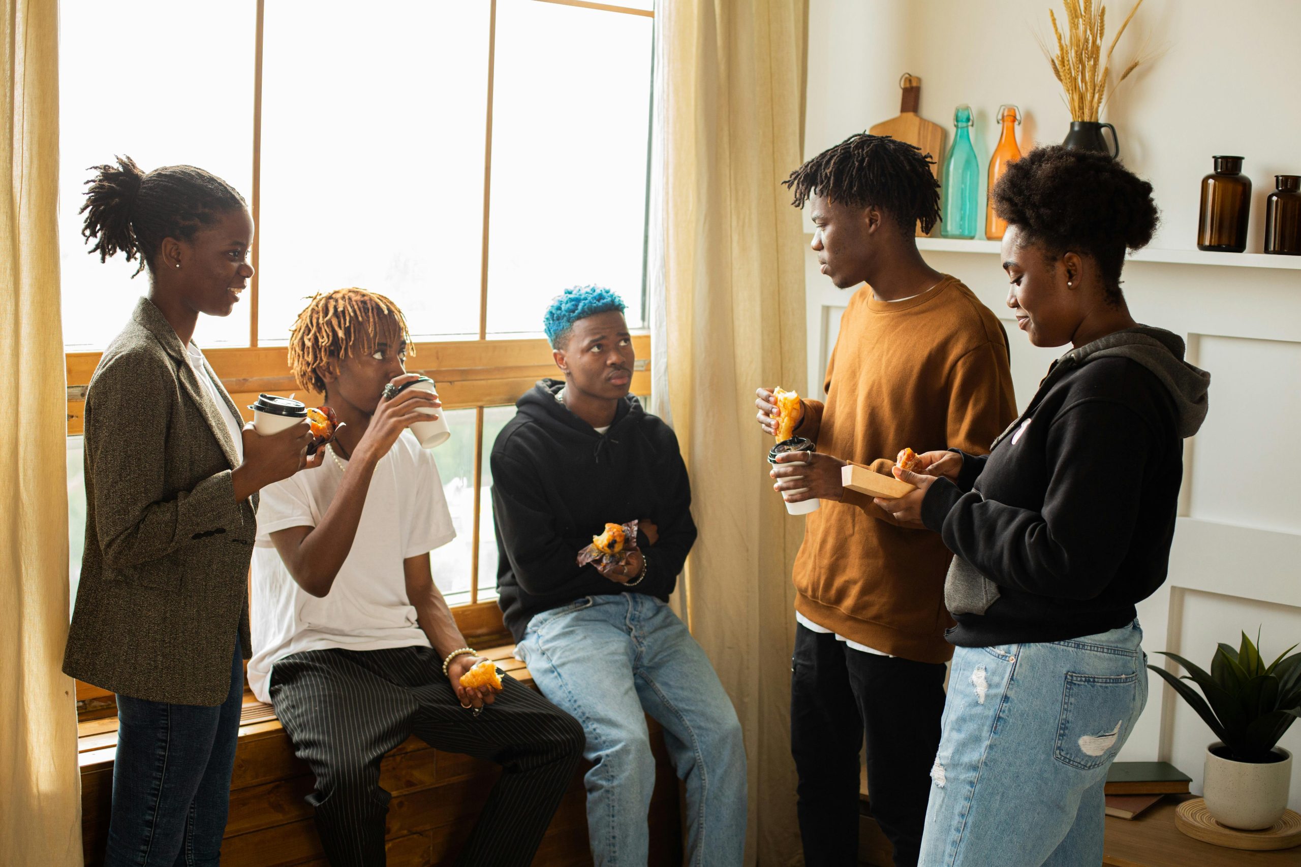 A diverse group of friends chatting and enjoying coffee indoors during the day.